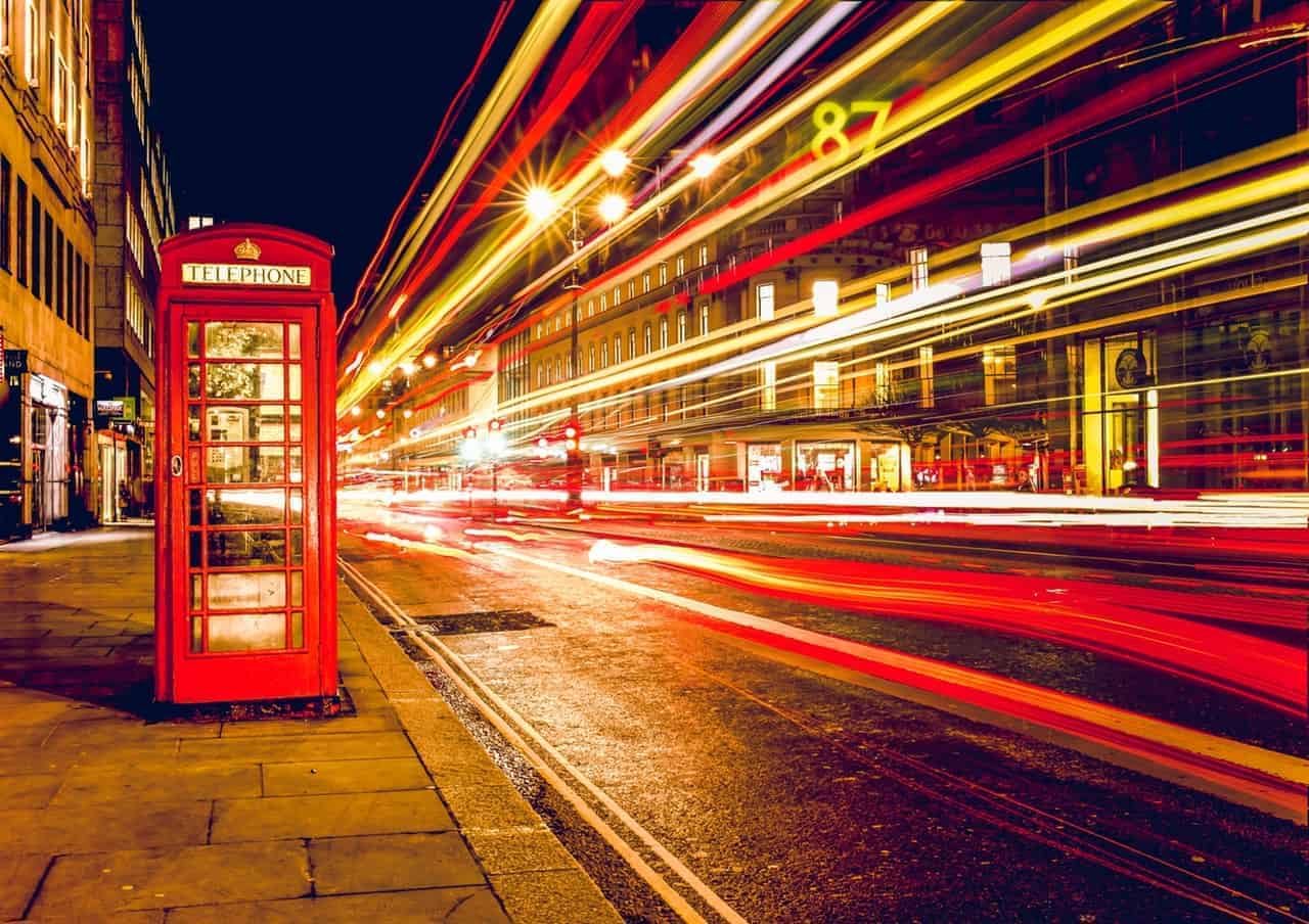 London red telephone box static next to timelapse blurred lights at night